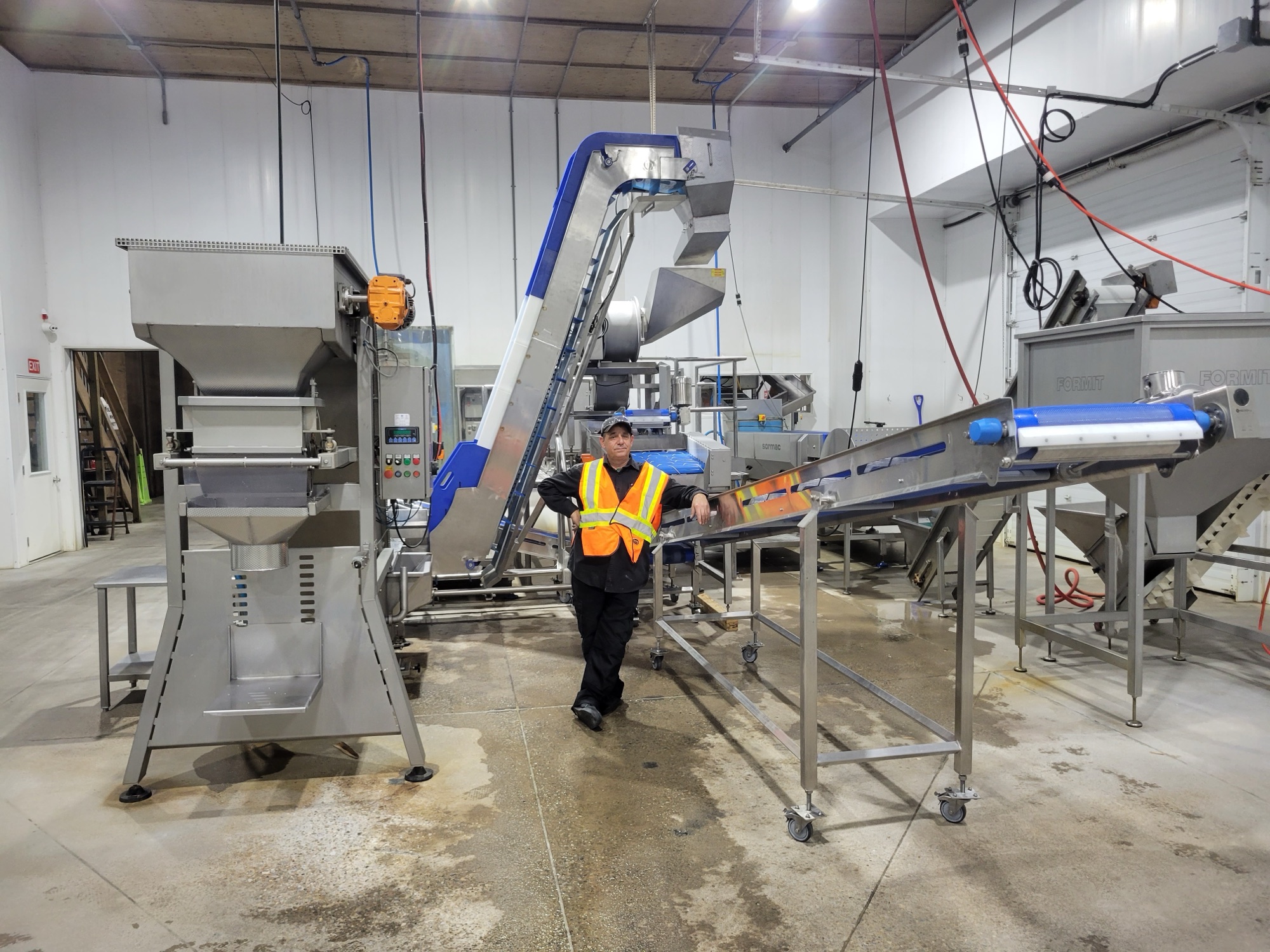 Operator beside an installed stainless conveyor line