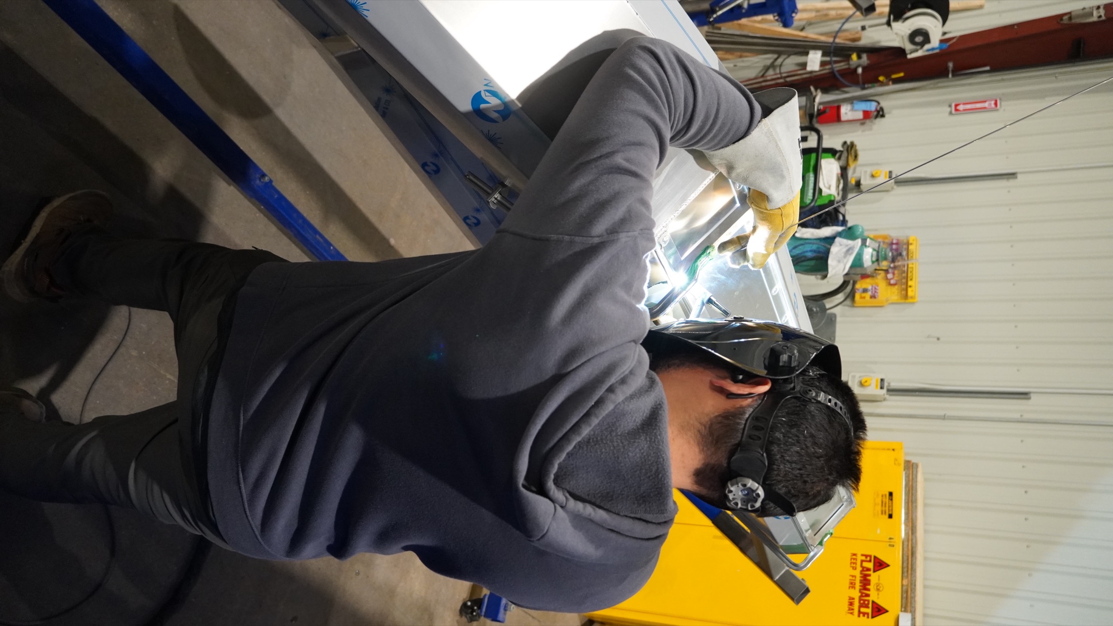 Shop worker welding polished sheet metal